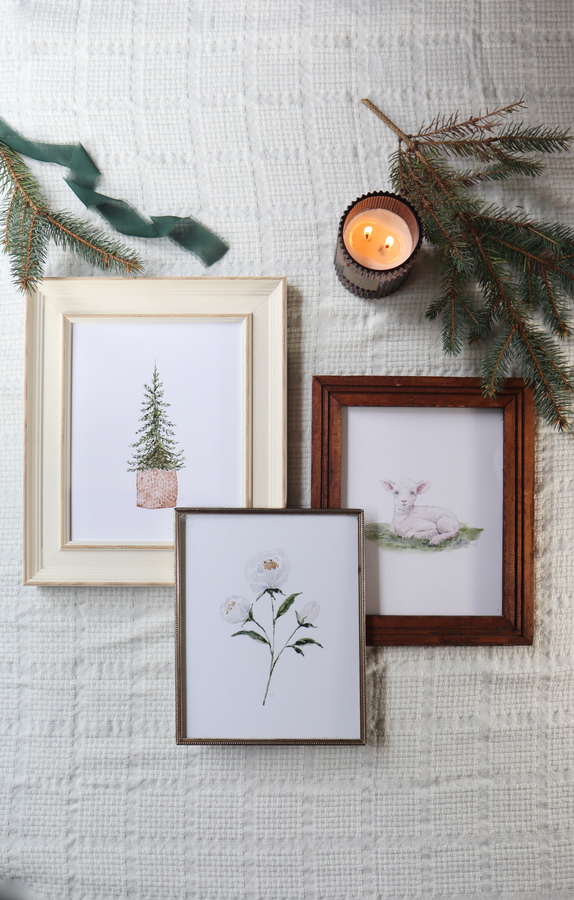 Framed prints of nature scenes on a textured wall with candles and greenery.