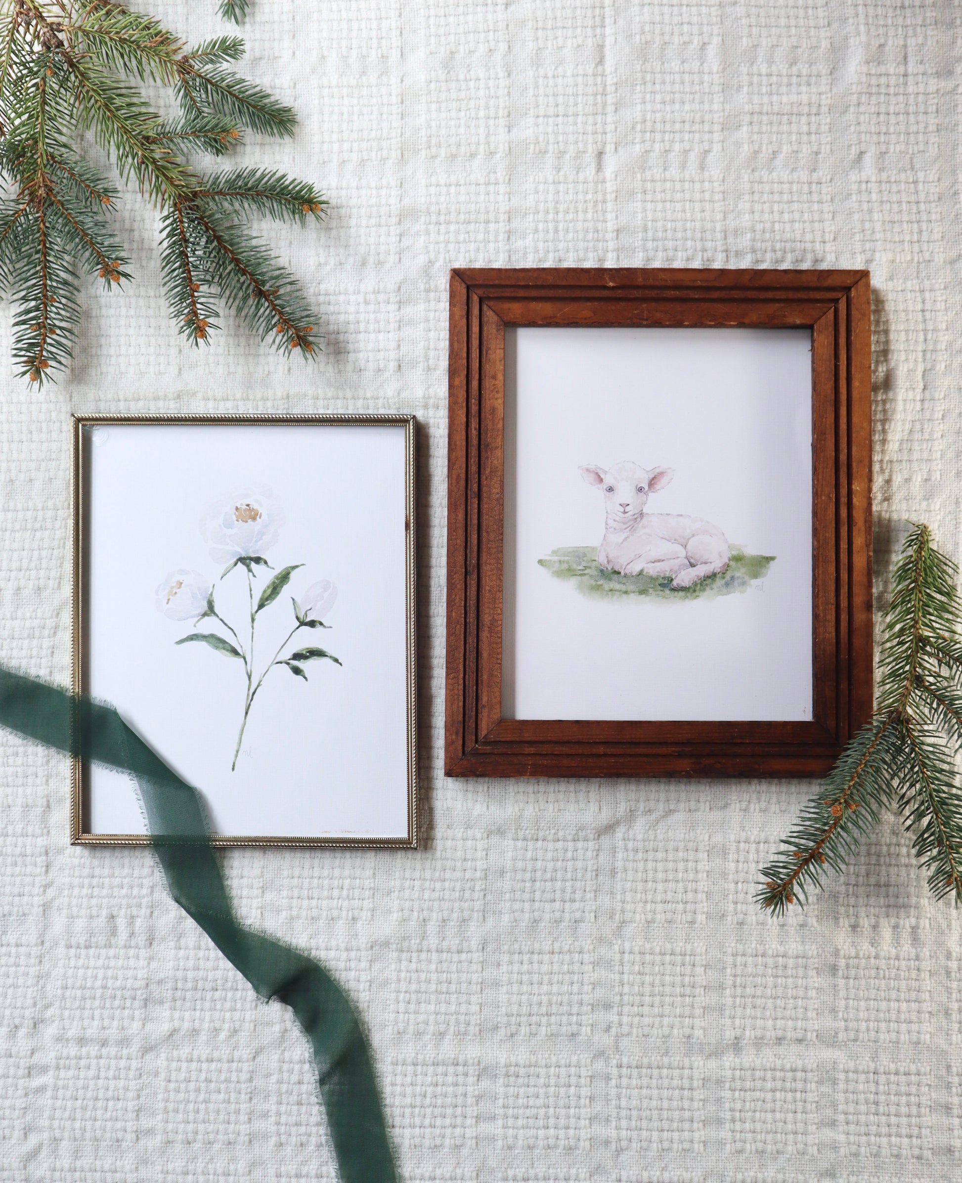 Two framed artworks on a textured wall with greenery.